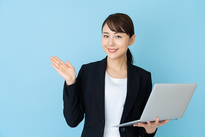 ノートパソコン片手に説明する女性