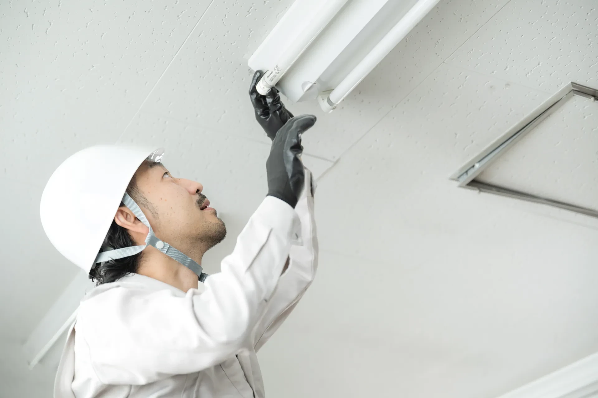 天井の照明器具を一人で交換する社員