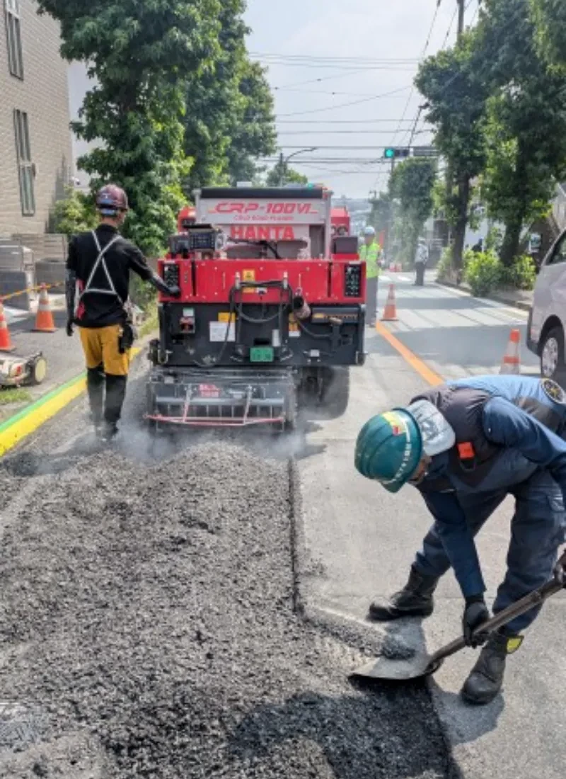 住宅街の路面を敷きならす職人と施工機械