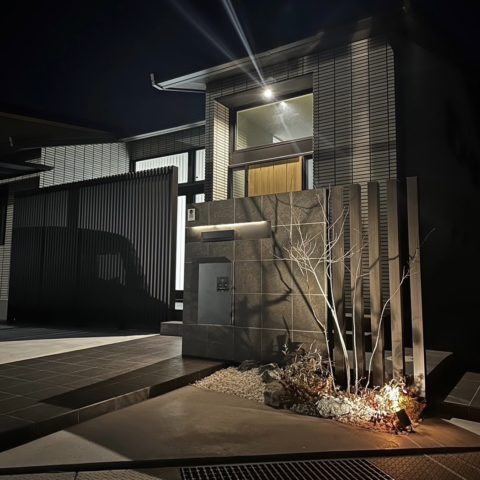 丸亀市で施工した、間接照明が陰影を描く石調タイルの門柱の写真