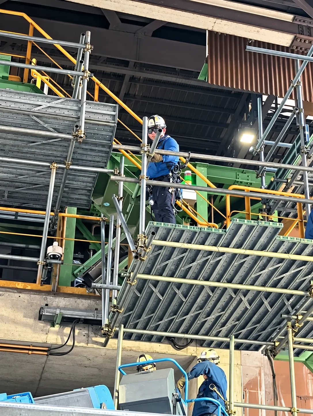 足場の上で安全確認をしながら作業する職人