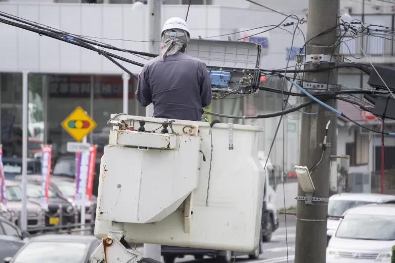 電柱上で通信ケーブル工事を行う作業員