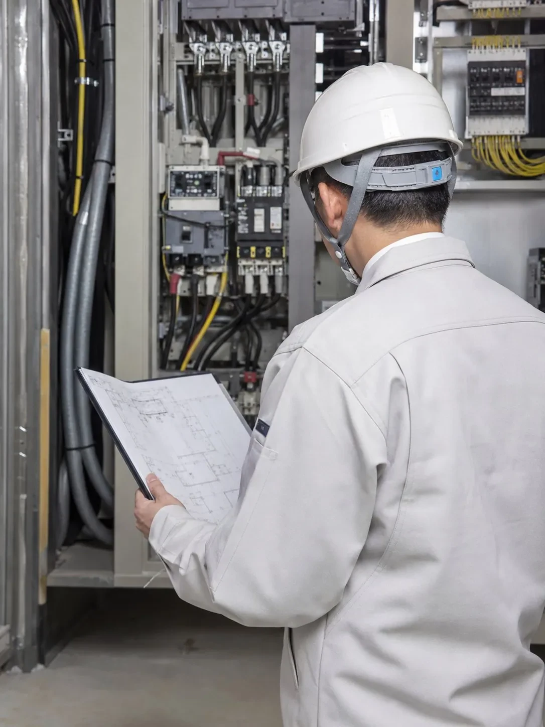 分電盤の前で図面を確認する施工管理者