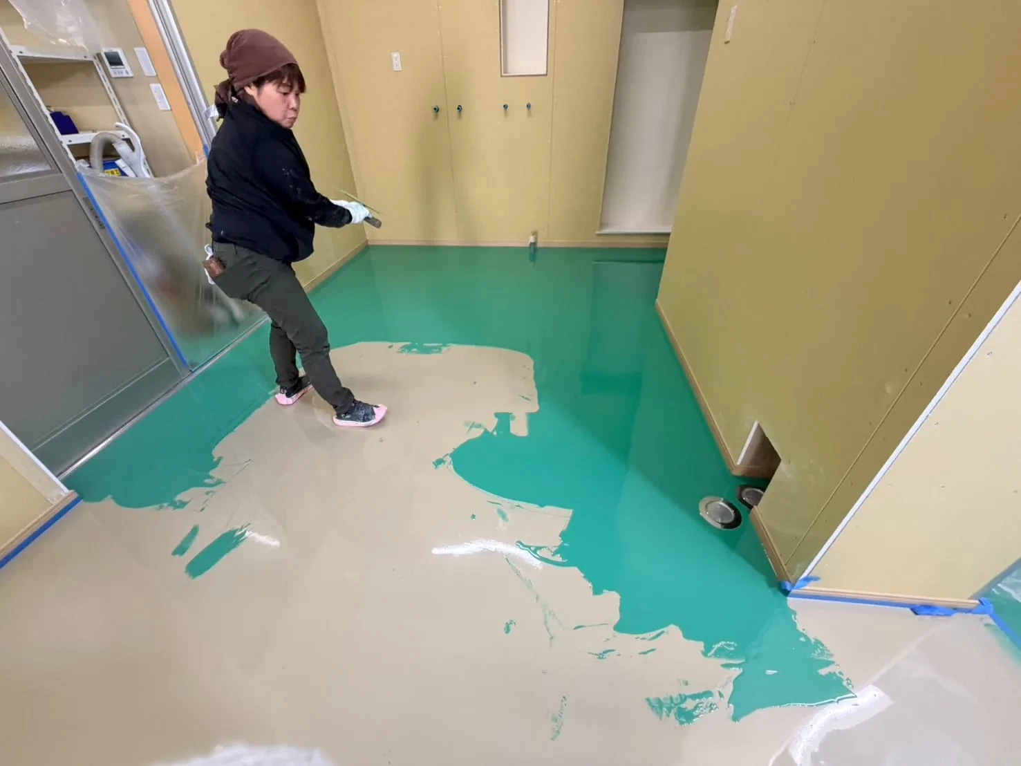 塗床材を床に流して広げる職人