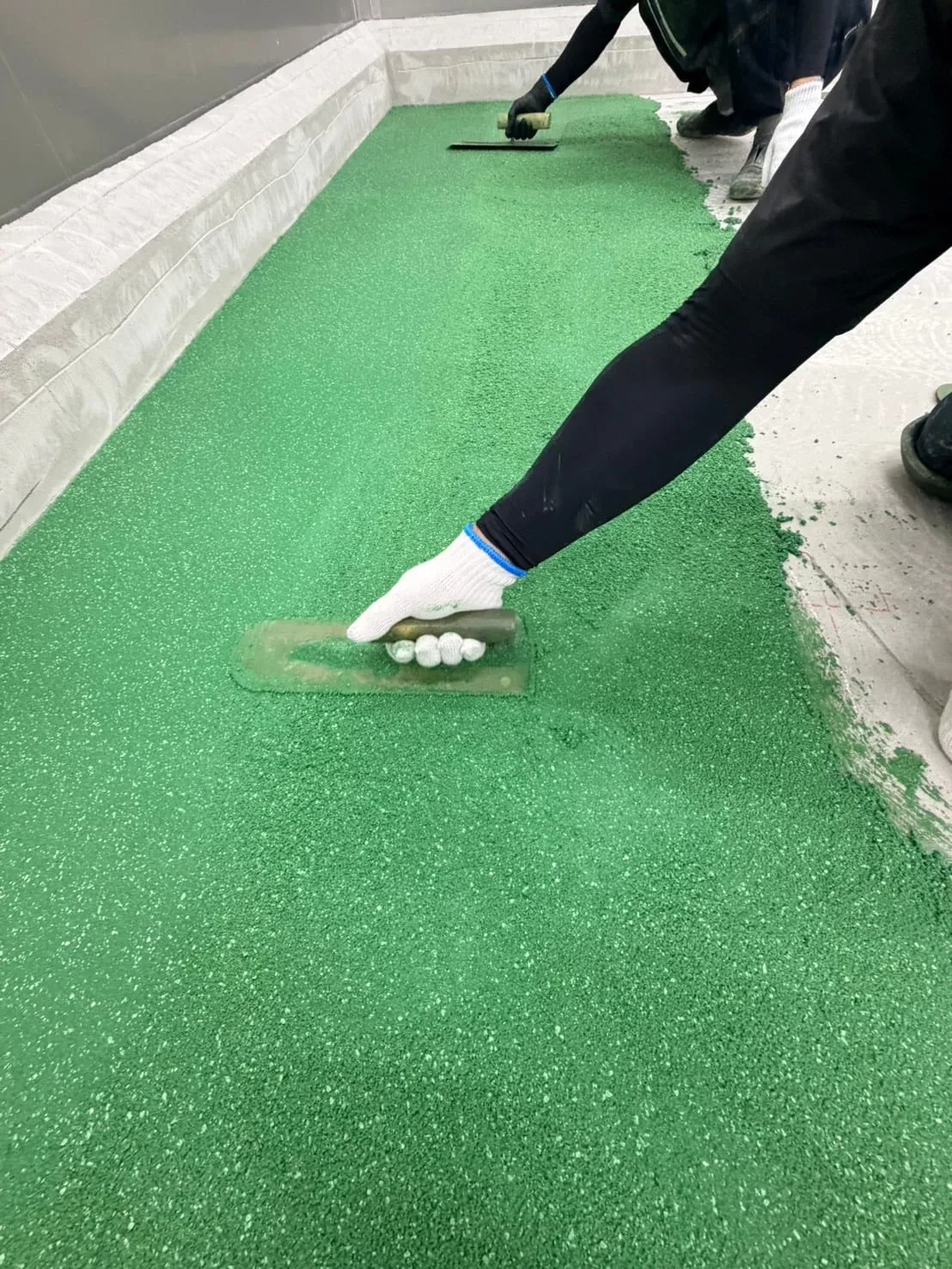 コテで防滑材を塗り広げる職人の手元