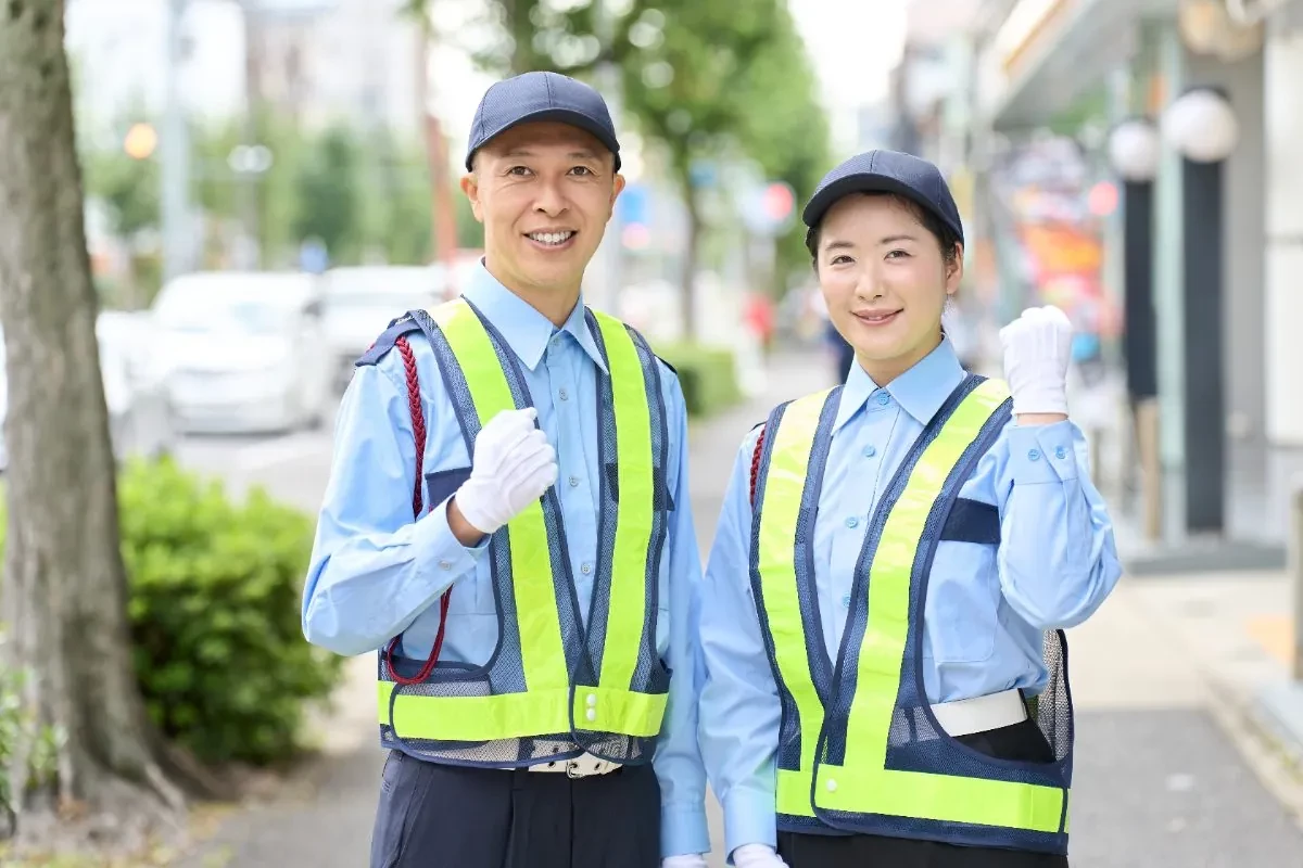 街頭に並んで立つ先輩と新人の警備員
