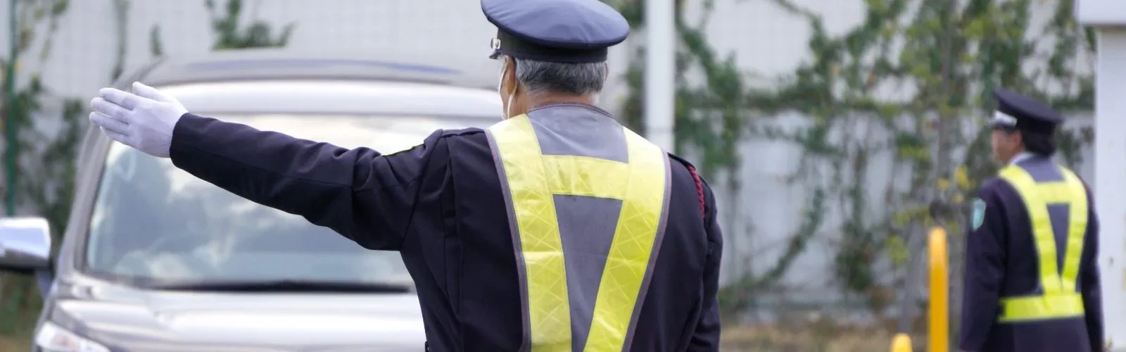 駐車場の出入口で車両を誘導する警備員