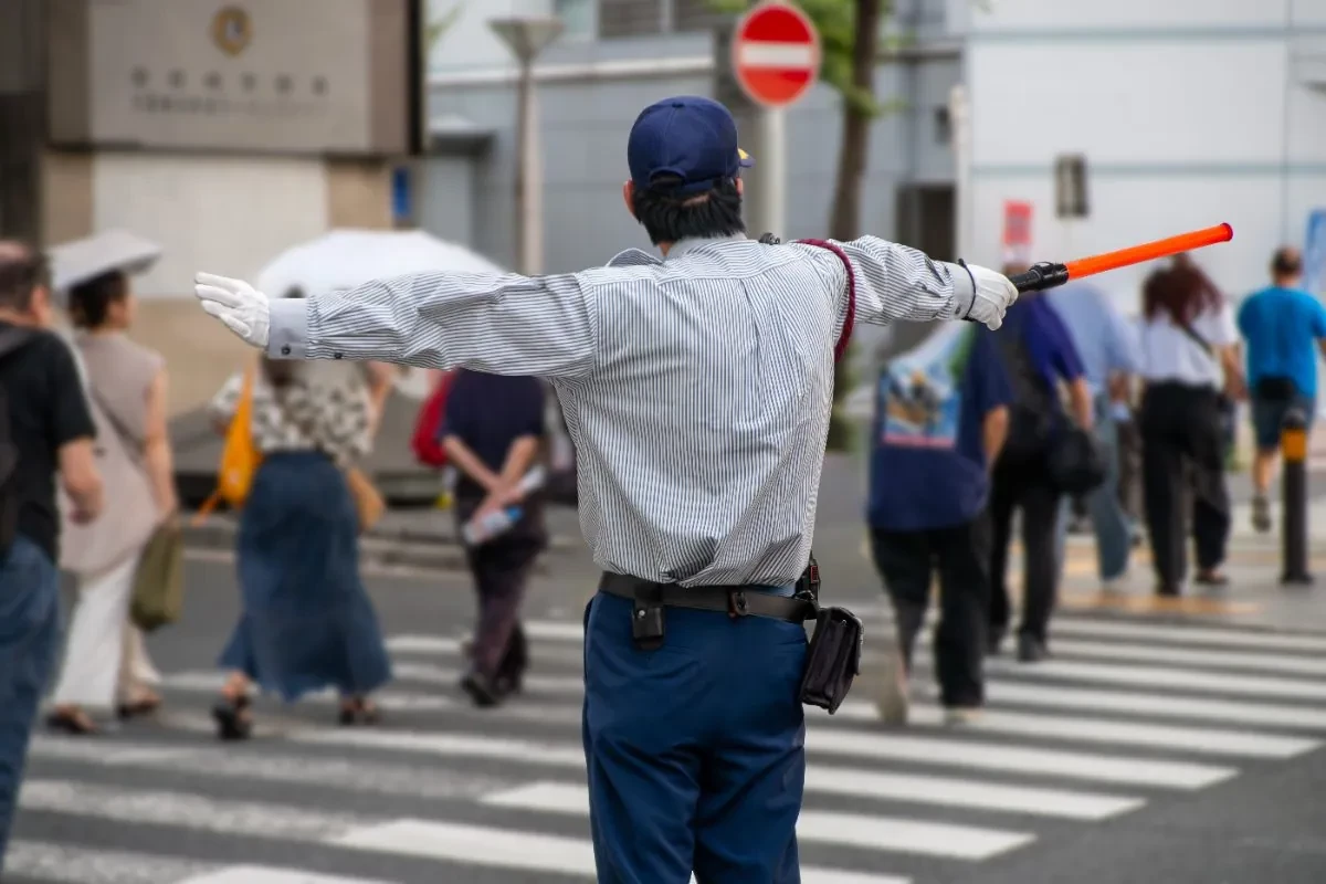 横断歩道で歩行者を誘導する警備員