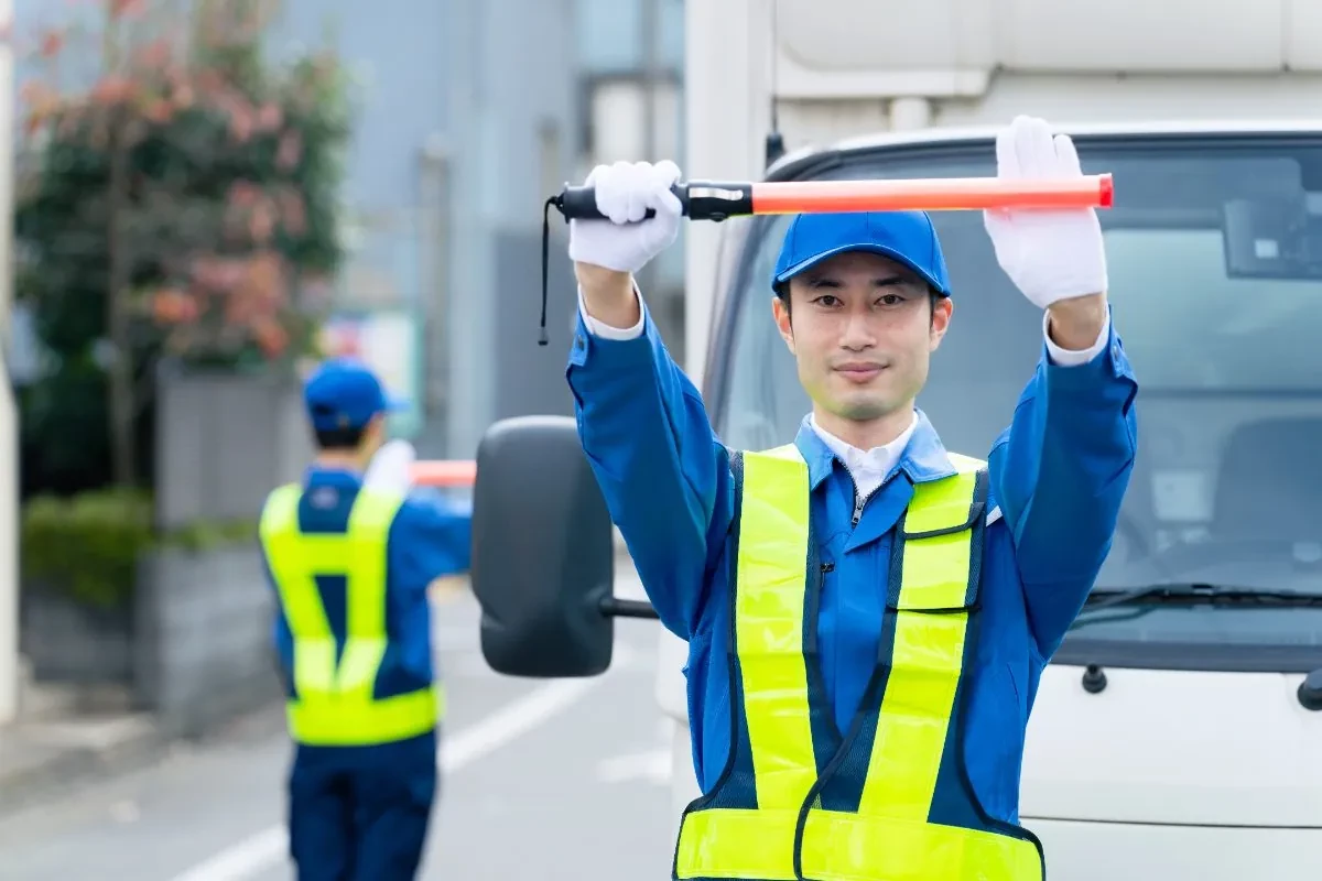片側交互通行で車を誘導する交通誘導警備員