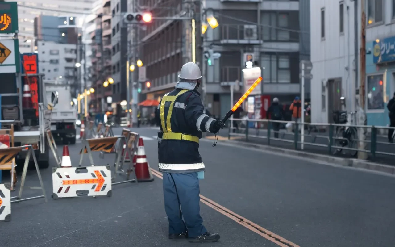 夕方の市街地で誘導灯を持ち車を誘導する隊員