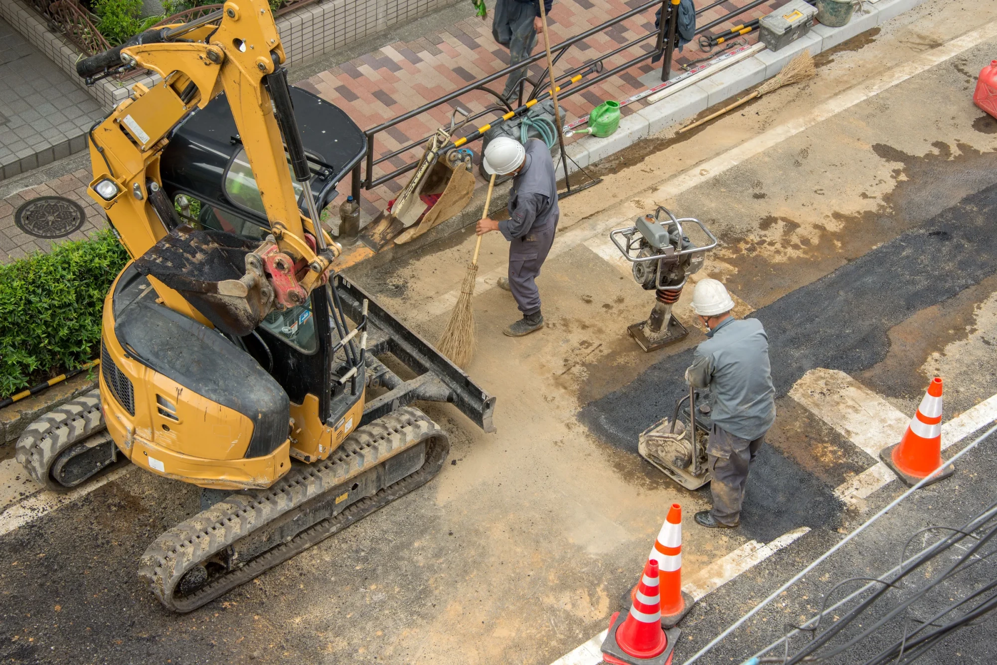 道路上で重機と作業員が連携して施工しているようす