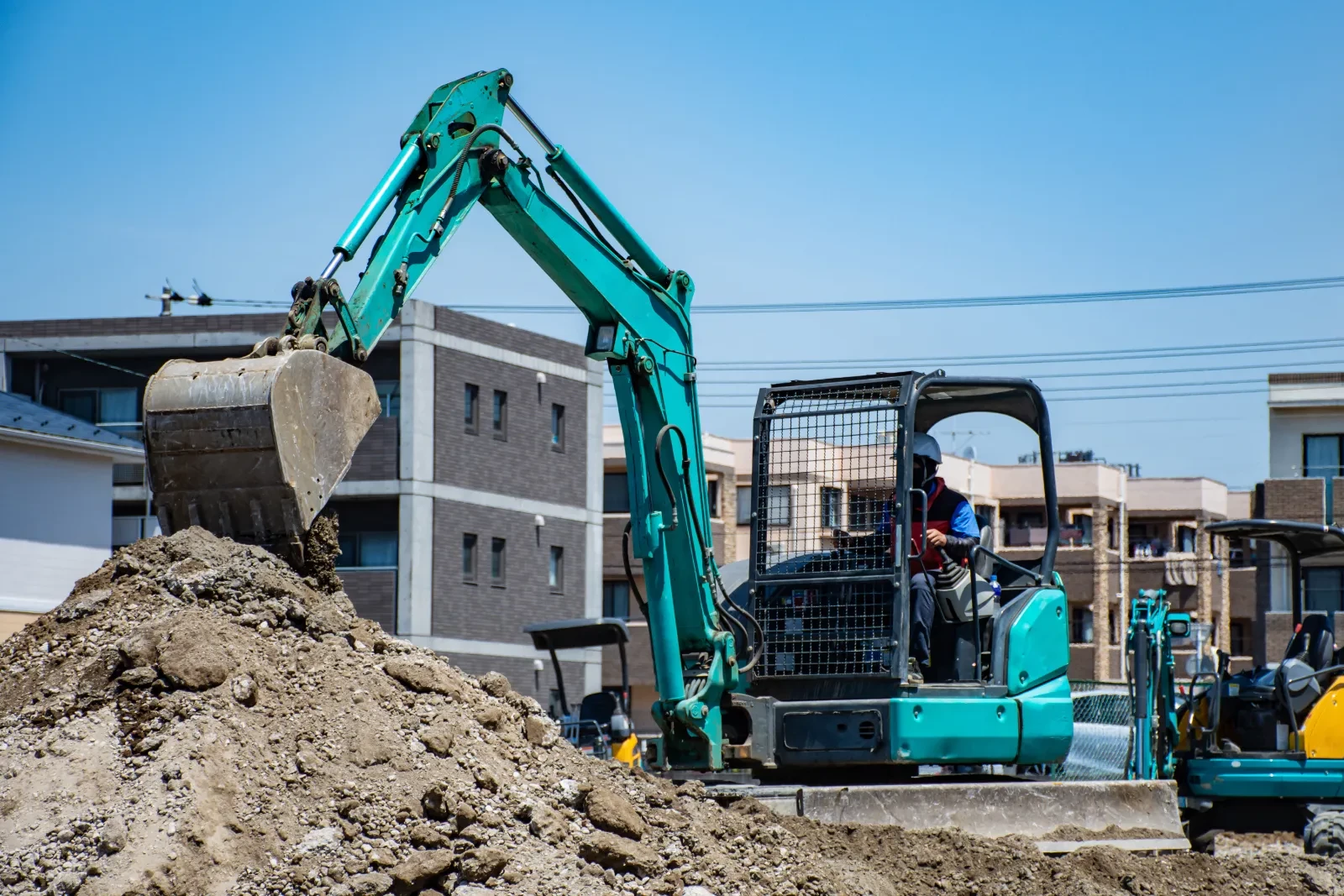 住宅地でミニショベルが土を掘削しているようす