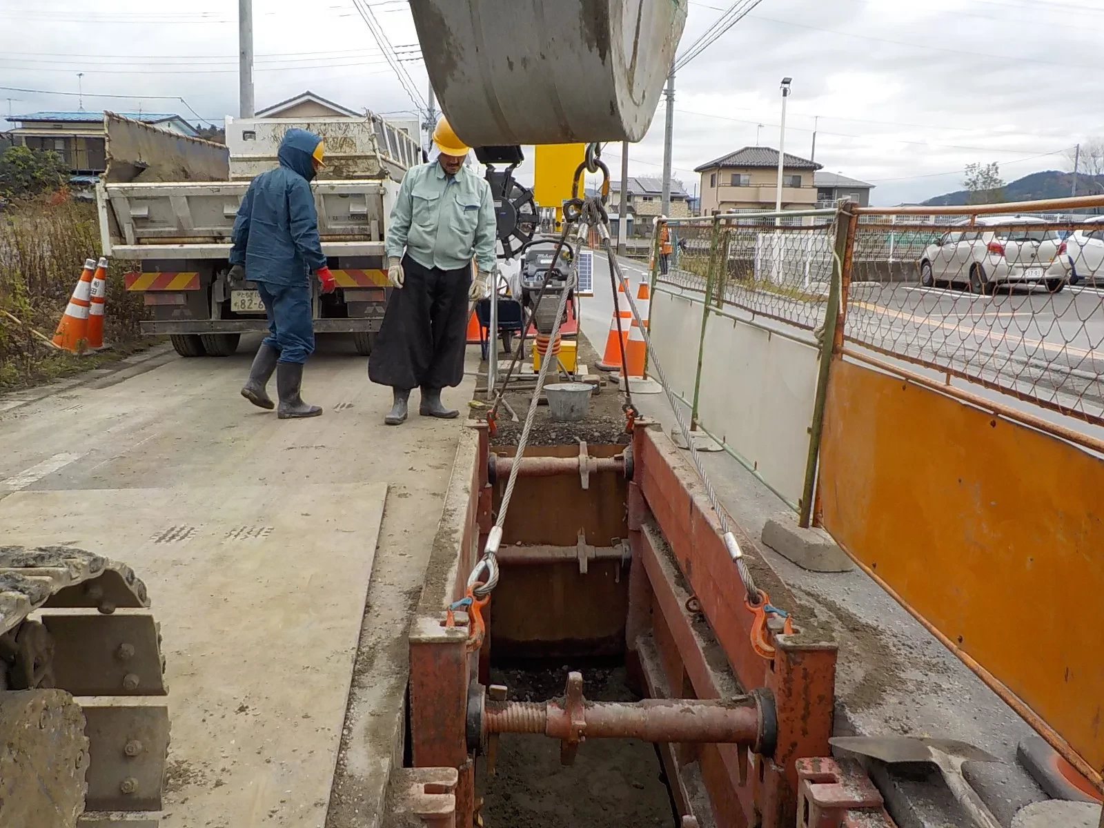 道路の掘削現場で土留めの設置作業を進める社員
