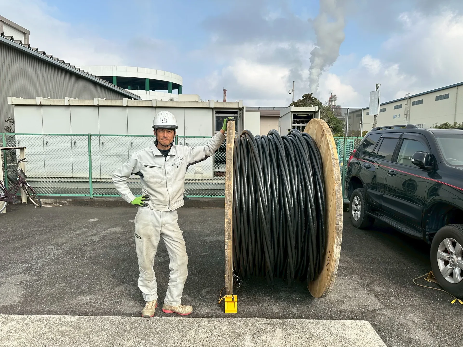 ケーブルドラムの前に立つ長谷川電気のスタッフ