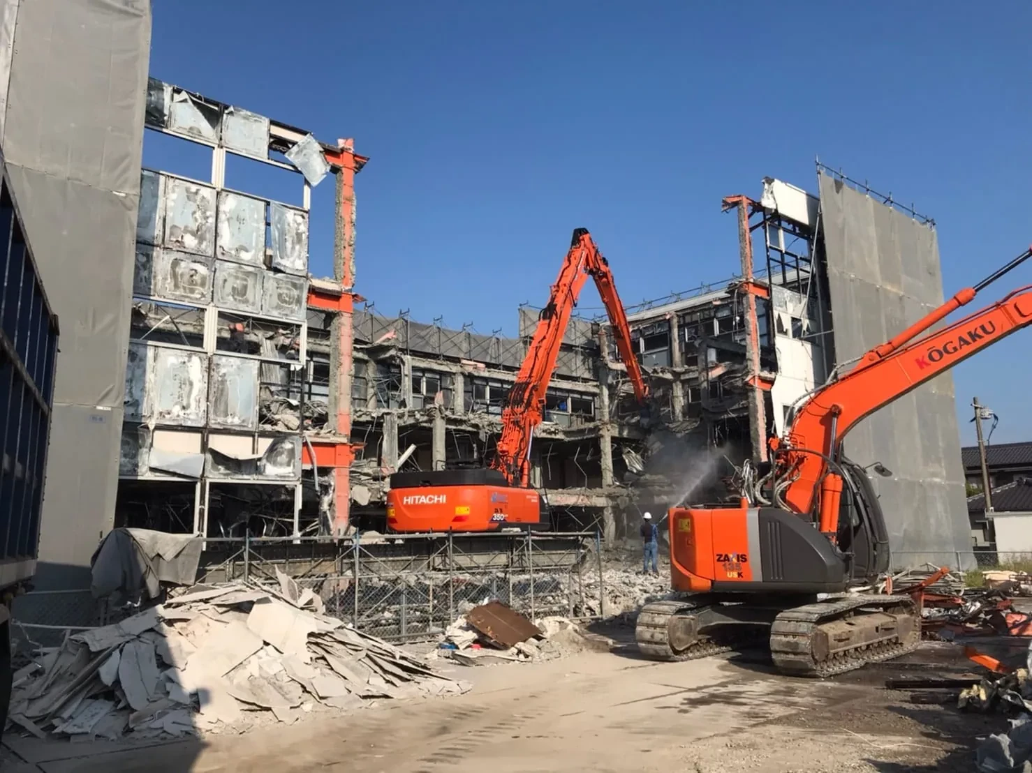 解体工事の現場でバックホウがRC造の建物を解体している様子