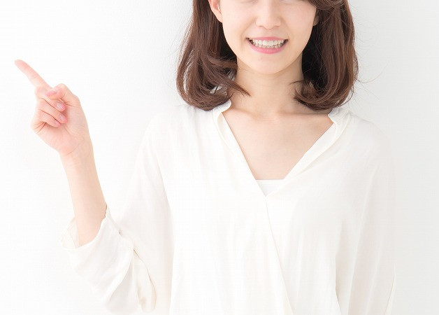 指を立てる白い服の女性